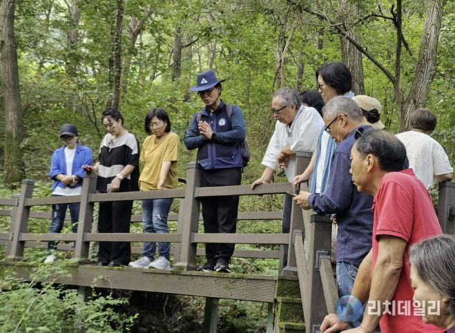 충북 괴산군 성불산 산림휴양단지에서 2025년 숲해설가가 방문객들에게 숲의 생태와 식생에 대해 설명하는 장면