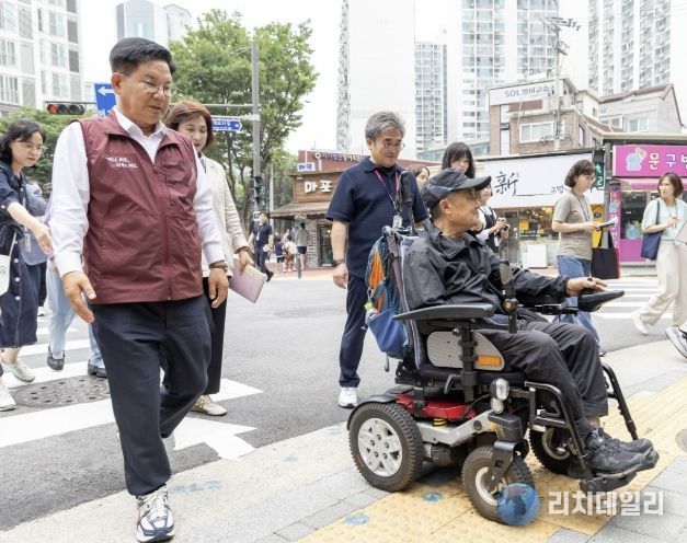 박강수 마포구청장이 휠체어를 탄 주민과 함께 새로 조성된 무장애길을 걷고 있다.