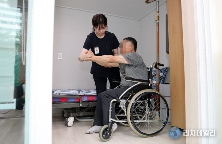 광산구 ‘살던집 프로젝트’ 기반 시설인 ‘중간집’에서 생활하는 주민이 작업 치료사의 도움으로 재활 운동을 하고 있다.